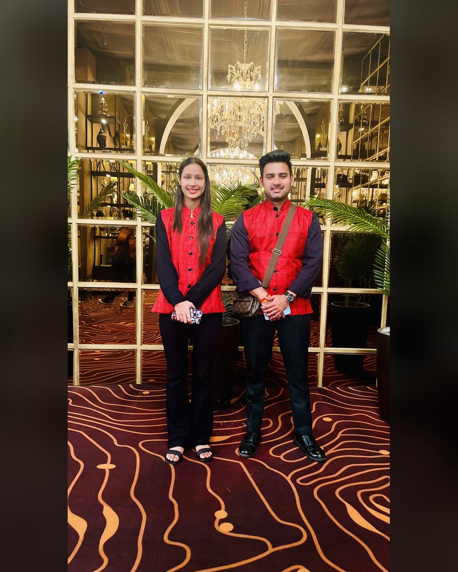 Wedding hosts in red Nehru jackets at a hotel lobby